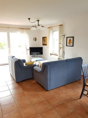 Een moderne woonkamer met een bank, televisie en een eethoek.