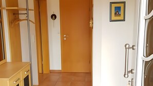 A hallway with a wooden door, a framed picture on the wall, and a blue mat leading to a room. - Holiday Home 'House Kiki in Dornumersiel' with Private Terrace, Private Garden and Wi-Fi (Dornum)