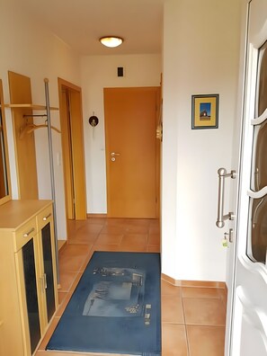Ein Flur mit einer Holztür, einem gerahmten Bild an der Wand und einer blauen Matte, die zu einem Zimmer führt.
