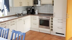 A kitchen with white cabinets, a microwave, a coffee maker, and a stove. - Holiday Home 'House Kiki in Dornumersiel' with Private Terrace, Private Garden and Wi-Fi (Dornum)