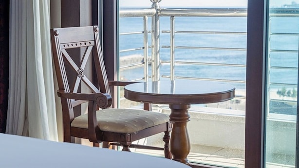 Une piĂšce avec vue sur lâocĂ©an, une chaise en bois et une table ronde.