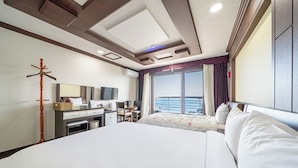 Une chambre dâhĂŽtel avec un grand lit, un bureau avec une chaise, un tĂ©lĂ©viseur Ă Ă©cran plat, un porte-manteau et une fenĂȘtre donnant sur la mer.