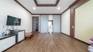 Une chambre dotĂ©e dâune kitchenette, dâune tĂ©lĂ©vision, dâune armoire et dâune salle de bain accessible par une porte coulissante.