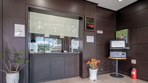 Un comptoir dâaccueil avec une horloge numĂ©rique, un extincteur et une petite table sur laquelle se trouve un Ă©cran.