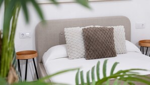 A neatly made bed with a headboard, two bedside tables, and a potted plant. - Mamalú Apartment: New, Romantic & Central in Jerez (Jerez de la Frontera)
