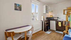 A compact kitchen with a dining area, a window, and a small refrigerator. - Bed and Breakfast 'Le Studio Miroir Aux Fées Bordeaux' with Wi-Fi (Bordeaux)