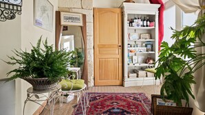A cozy room with a wooden door, a bookshelf, a patterned rug, and various plants. - Bed and Breakfast 'Le Studio Miroir Aux Fées Bordeaux' with Wi-Fi (Bordeaux)