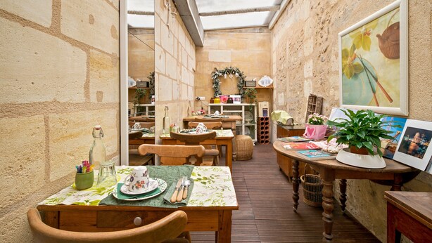 A cozy patio area with wooden tables and chairs, a green tablecloth, and a potted plant. - Bed and Breakfast 'Le Studio Miroir Aux Fées Bordeaux' with Wi-Fi (Bordeaux)