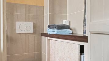 Une salle de bain équipée d’un porte-serviettes, d’un support à papier toilette et d’un espace douche.