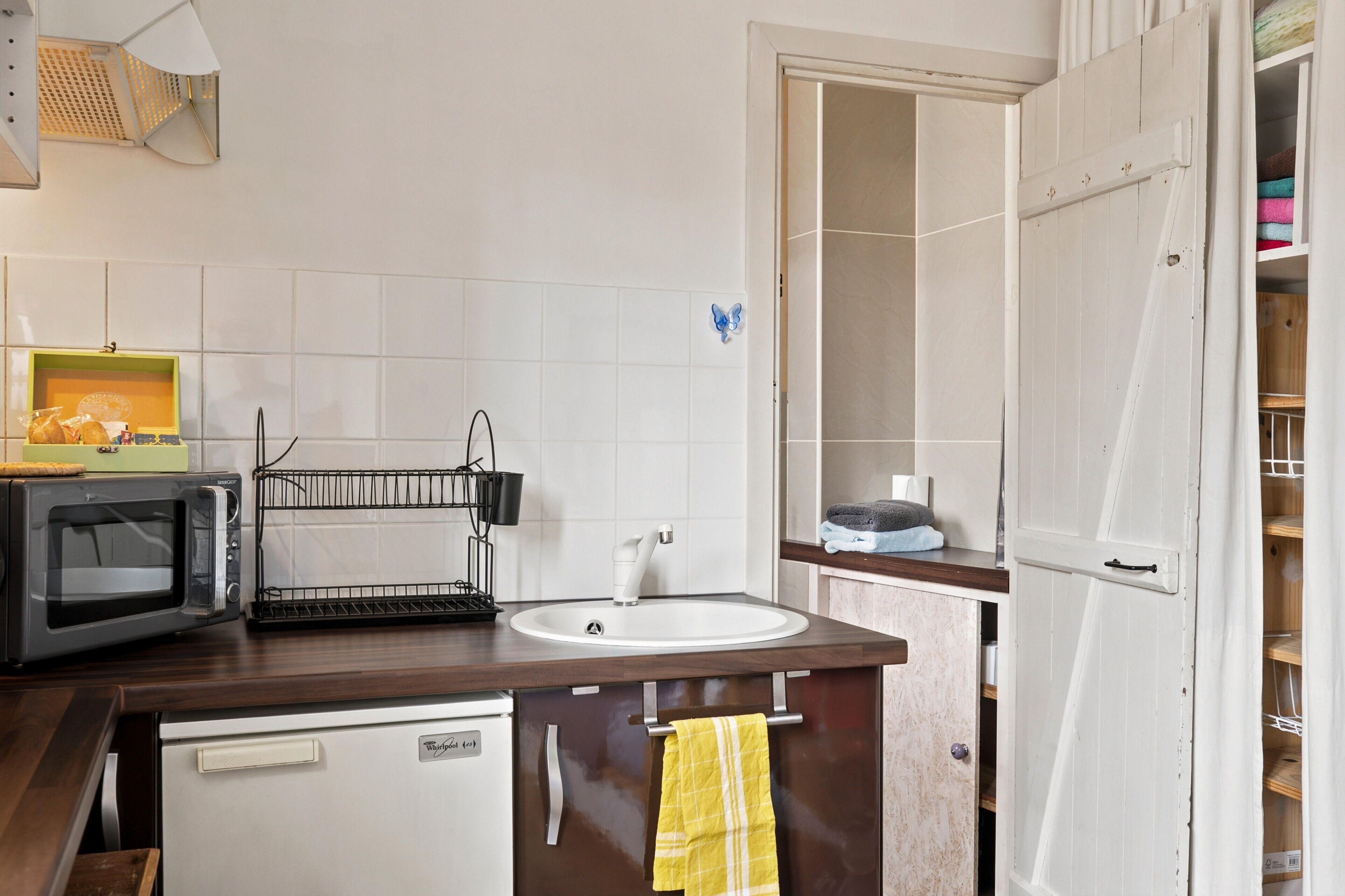 A compact kitchen with a microwave, sink, and a small refrigerator.