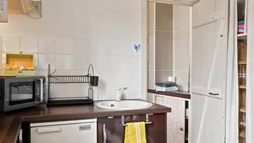 A compact kitchen with a microwave, sink, and a small refrigerator.