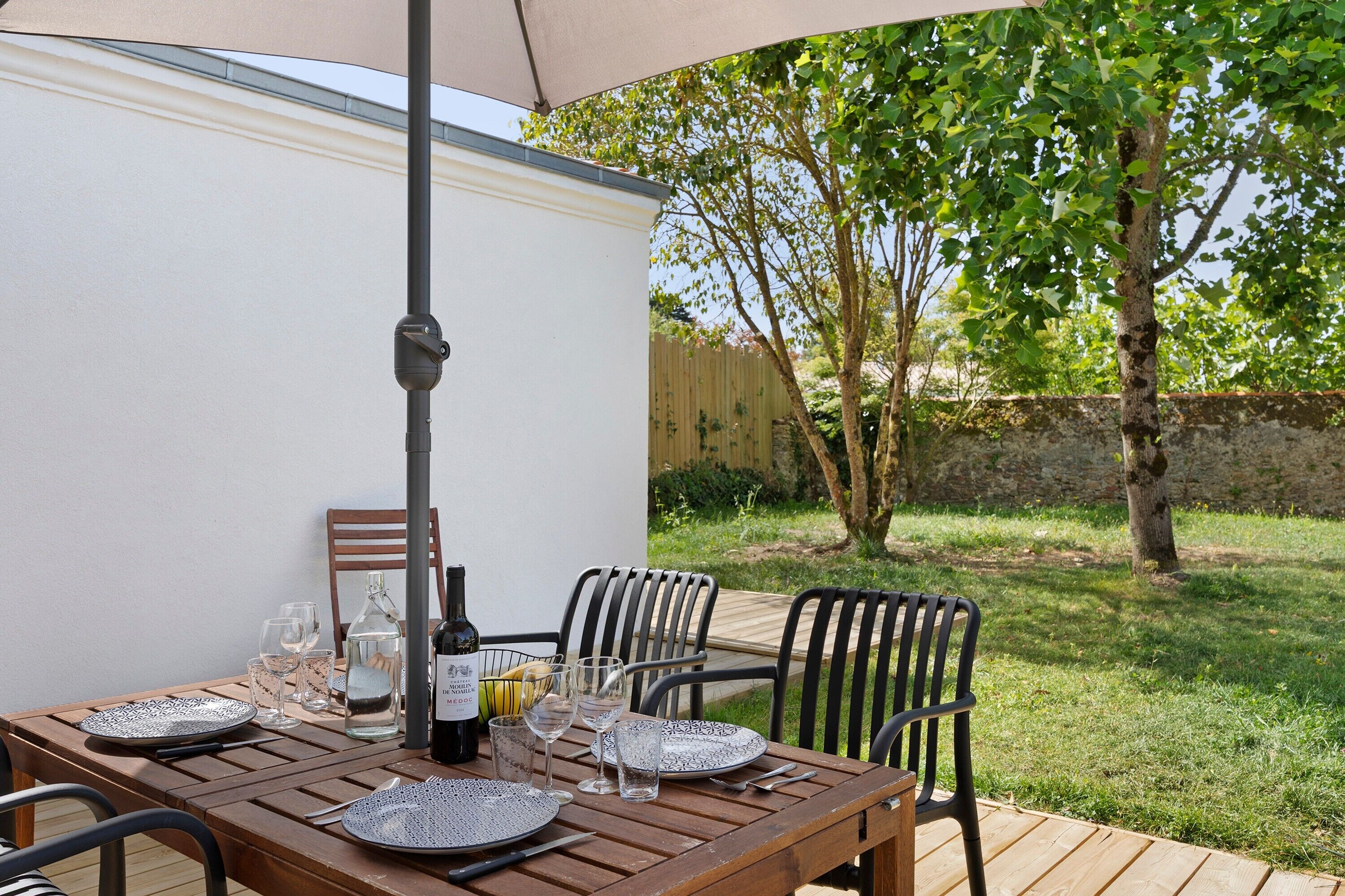 An outdoor dining area with a wooden table, chairs, and a table umbrella.
