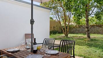 An outdoor dining area with a wooden table, chairs, and a table umbrella.
