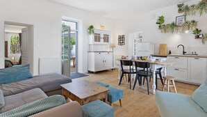 A modern kitchen with white cabinets, a dining table, and chairs, and a living area with sofas and a coffee table.