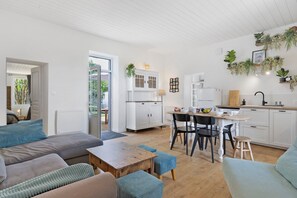 Eine moderne Küche mit weißen Schränken, einem Esstisch, Stühlen und einer Wohnbereich mit Sofas und einem Couchtisch.
