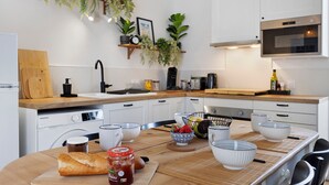 Eine moderne Küche mit weißen Schränken, einer Holz Arbeitsplatte, einem eingebauten Ofen und einem Essbereich mit einem Holztisch und Stühlen.