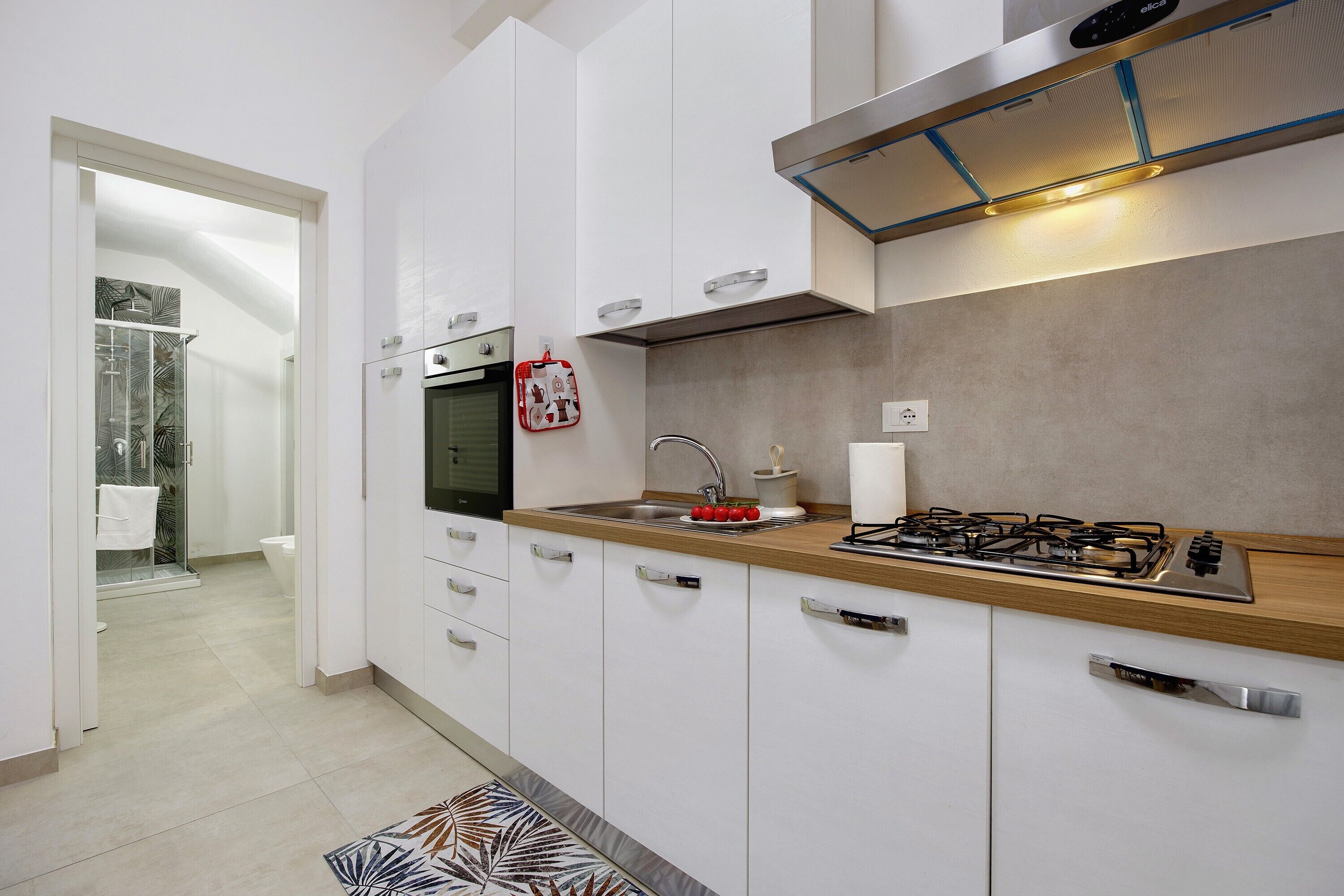 A modern kitchen with white cabinets, a stainless steel stove, and a red kettle.