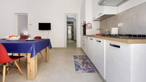 Eine moderne Küche mit weißen Schränken, einem Gasherd und einem Essbereich mit blauer Tischdecke und roten Stühlen.