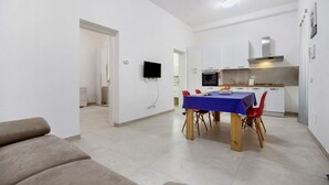 Eine moderne Küche mit weißen Schränken, einem blauen Tisch und roten Stühlen.