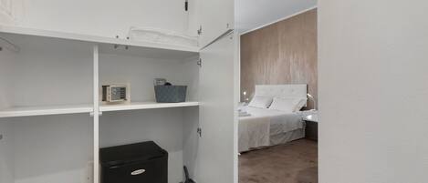 A hotel room with a bed, a nightstand, a lamp, and a wardrobe with a small appliance.