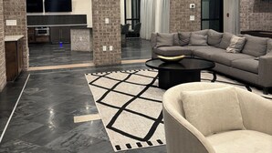 Un hall d’entrée moderne avec une arche en pierre, un canapé d’angle, une table basse et un tapis à motifs.