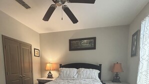 A bedroom with a bed, a ceiling fan, a nightstand with a lamp, a door, and a framed picture on the wall. - Luxury/Cozy 1-Bedroom Condo Retreat Dunwoody GA (Dunwoody)
