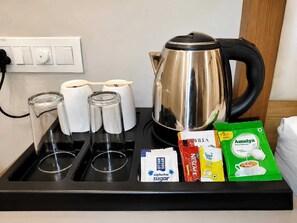 A kitchen counter with a kettle, sugar packets, and a coffee maker. - HOTEL MUDITA BY KIRTI (Patna)