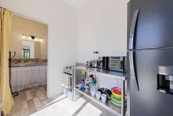 Una cocina compacta equipada con refrigerador, estufa y cafetera.