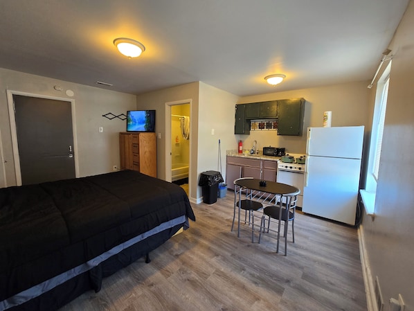 A compact hotel room with a bed, a small kitchenette, a TV, and a bathroom. - Lovely Studio Apartment Near Philadelphia (Camden)