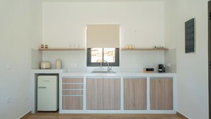 A compact kitchen with a refrigerator, a sink, and wooden cabinets.