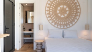 A bedroom with a bed, a round wall hanging, a bedside table, and a door leading to a bathroom.