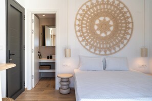 A bedroom with a bed, a round wall hanging, a bedside table, and a door leading to a bathroom.