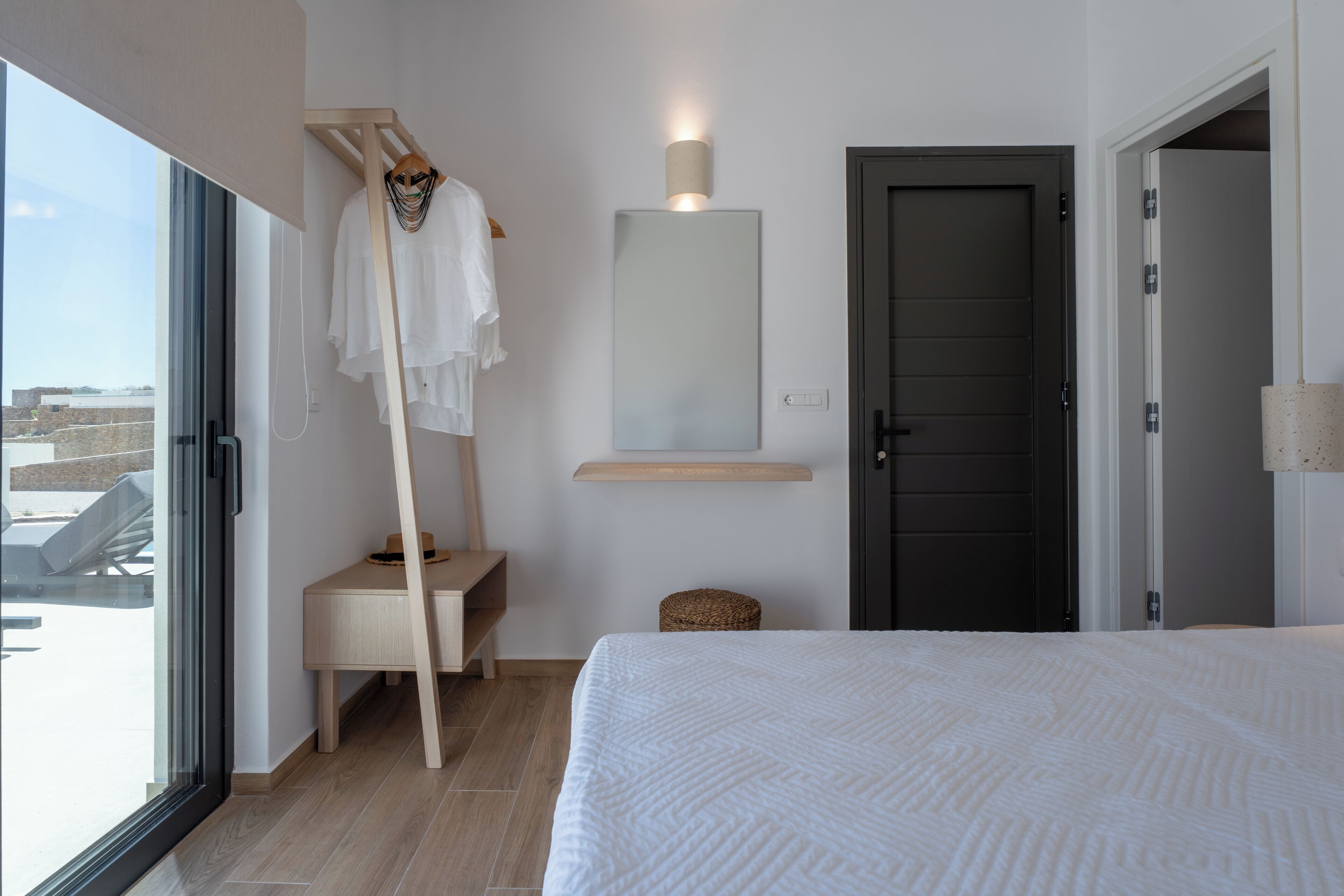 Un dormitorio con cama, espejo, puerta y ventana.
