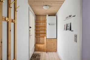 Ein schmaler Gang mit Holztritten, einer weißen Tür und einem weißen Kühlschrank.