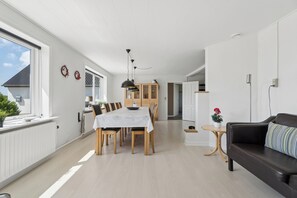 A modern living space with a dining area, a sofa, and a small table with a plant. - Spacious holiday home with water view (Redsted)