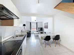 A modern kitchen with a stove, sink, and dining area with chairs.