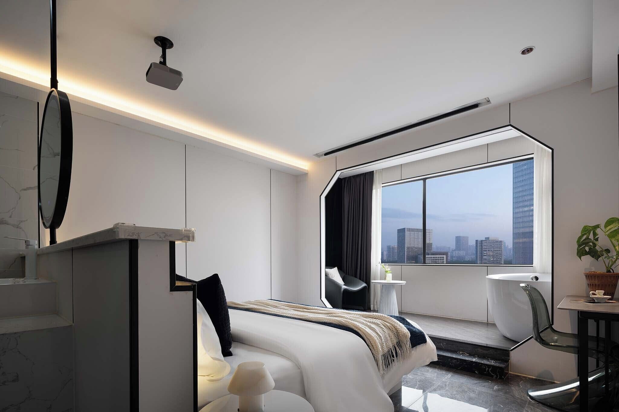 A modern hotel room with a large window, a bed, a chair, and a small table.