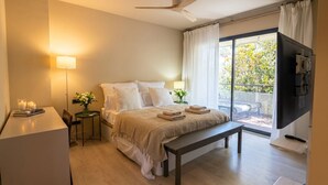 Una camera da letto con un letto, comodini, una scrivania, una panca, una TV e un balcone con vista.
