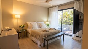 Ein Schlafzimmer mit Bett, Nachttischen, Schreibtisch, einer Bank, einem Fernseher und einem Balkon mit Blick.