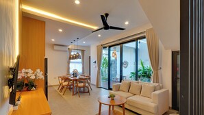 A modern living room with a sofa, a dining table, and a ceiling fan. - Villa Omara - Nusa Dua (Nusa Dua)