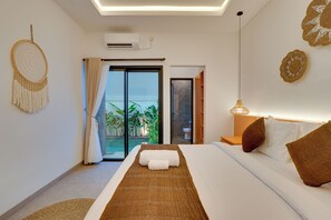 A modern hotel room with a bed, a view of the outdoors, a ceiling fan, and a wall-mounted air conditioner. - Villa Omara - Nusa Dua (Nusa Dua)