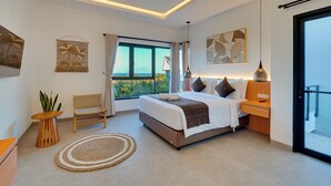 A modern bedroom with a large bed, a bedside table, a chair, a window with a view, and a ceiling light. - Villa Omara - Nusa Dua (Nusa Dua)