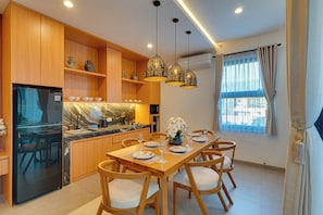Eine moderne Küche mit Holzschränken, einem eingebauten Kühlschrank und einer Essecke mit Tisch für vier Personen.