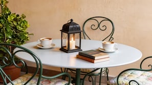 Ein runder Tisch mit zwei weißen Kaffeetassen, einer brennenden Kerze in einer Laterne und einem Stapel Bücher.
