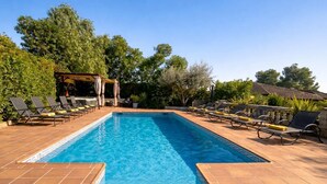 A rectangular swimming pool with tiled edges, surrounded by lounge chairs and a pergola with curtains. - 15 minutes by car / Sitges – Villa Ilus XXL Pool, A/C by Weekly Villas 15 P (Sitges)