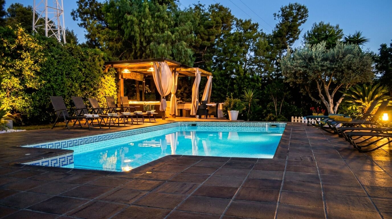 Piscina com deck revestido, espreguiçadeiras e área de estar coberta.