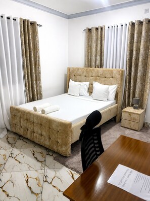 Un dormitorio con cama, mesita de noche, silla y escritorio.