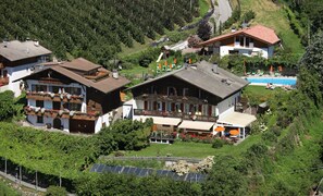 Un edifici gran amb múltiples balcons, una piscina i panells solars.