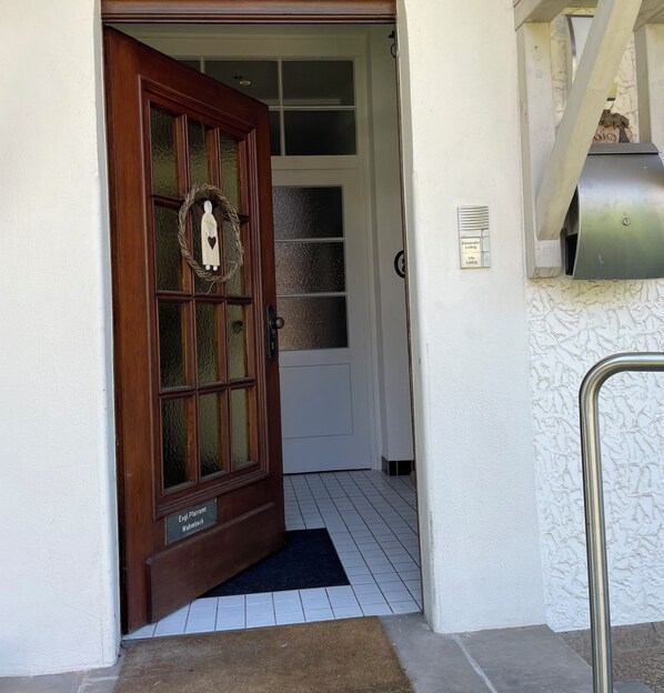 A wooden front door with a wreath, a mailbox, and a tiled entrance.