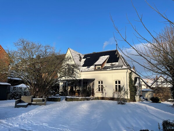 A house with a sloped roof, a front porch, and a snow-covered yard.